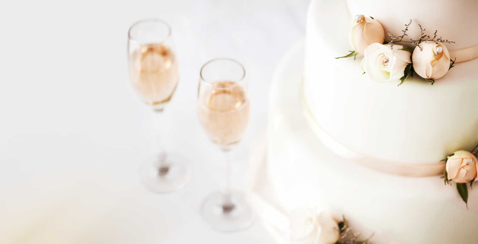 Two champagne flutes beside a tiered white wedding cake decorated with peach roses at a Stone Mountain wedding venue